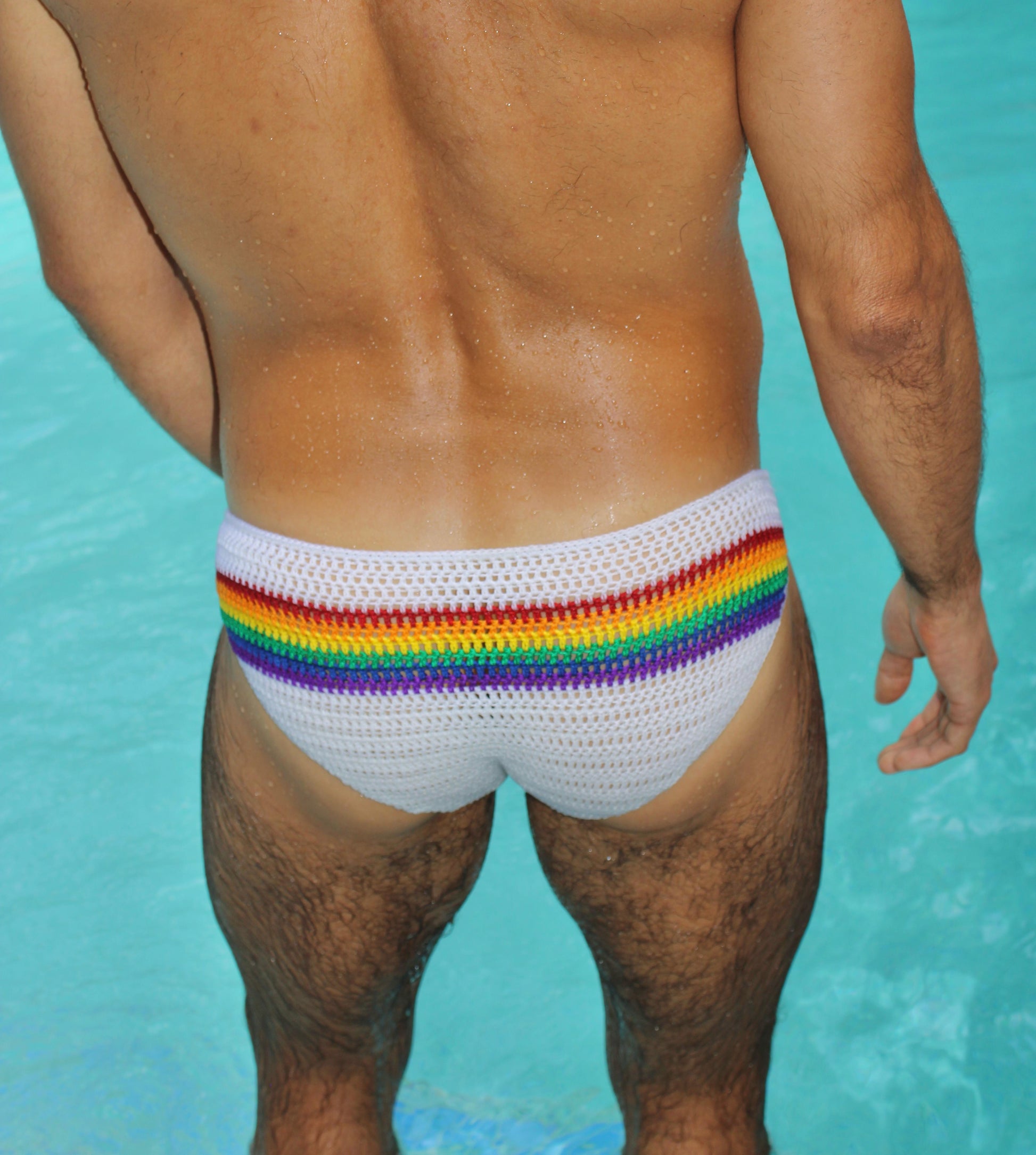 Back angled view of rainbow crochet men’s swim briefs, showing fit and colorful design.