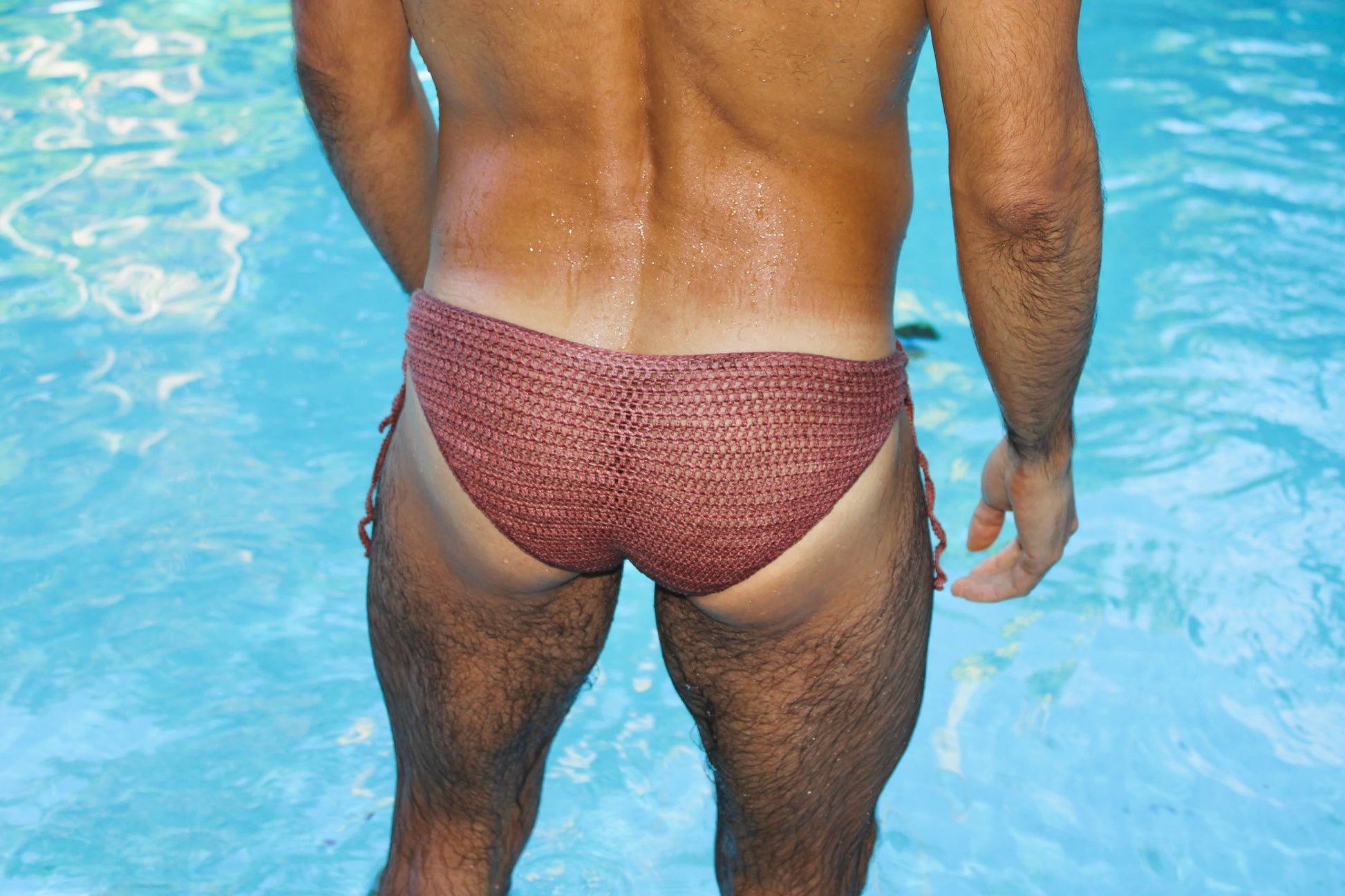 Lifestyle photo of men’s crochet tie-side swim briefs near the pool, showcasing summer beachwear.
