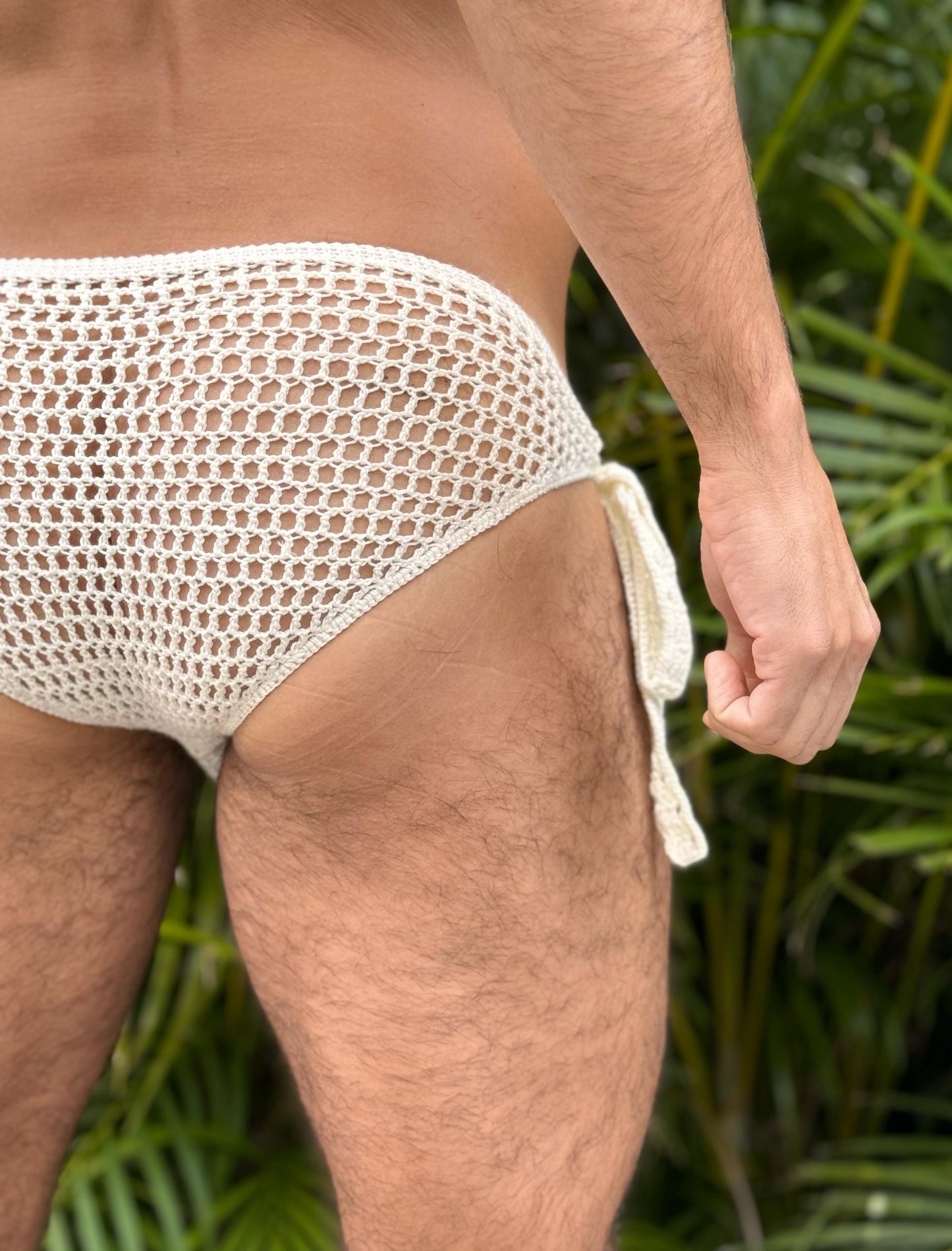 Back close-up of crochet briefs with side ties near the pool, highlighting airy open stitch design and snug comfort.