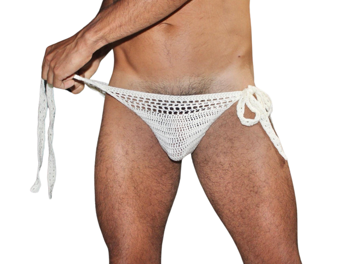 Man adjusting the side tie of crochet swim briefs, showing flexibility and detailed handmade craftsmanship.