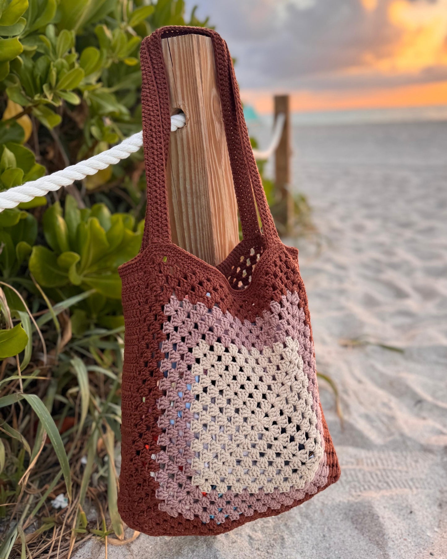 Front view of handmade crochet beach shoulder tote bag in cream color, displayed hanging on a hook.