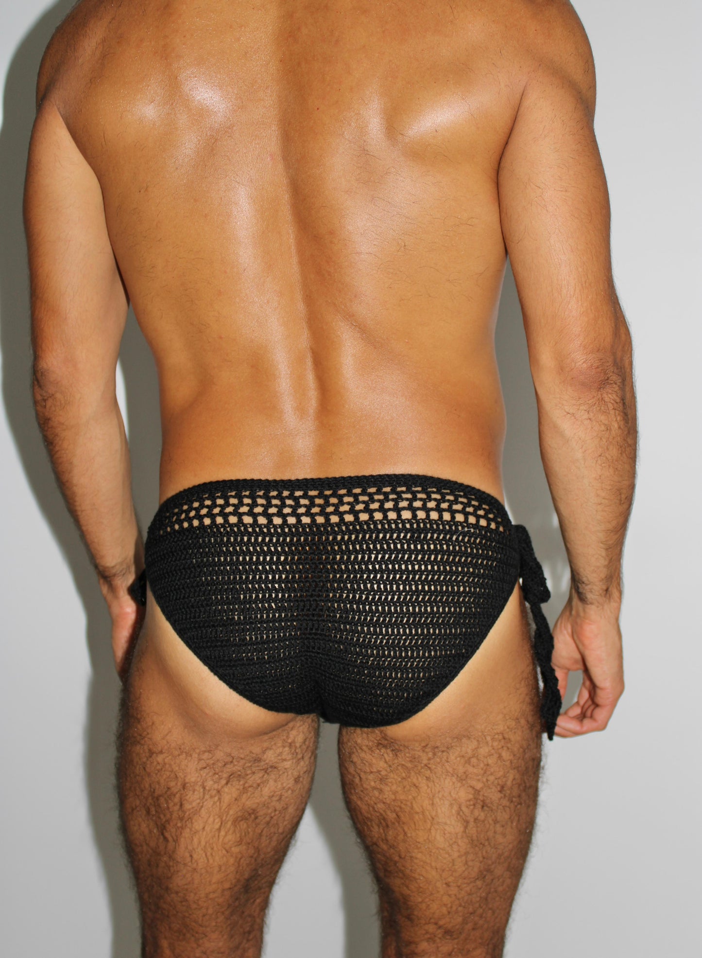 Back angled view of men’s tie side crochet swim briefs, emphasizing airy structure and comfortable fit.
