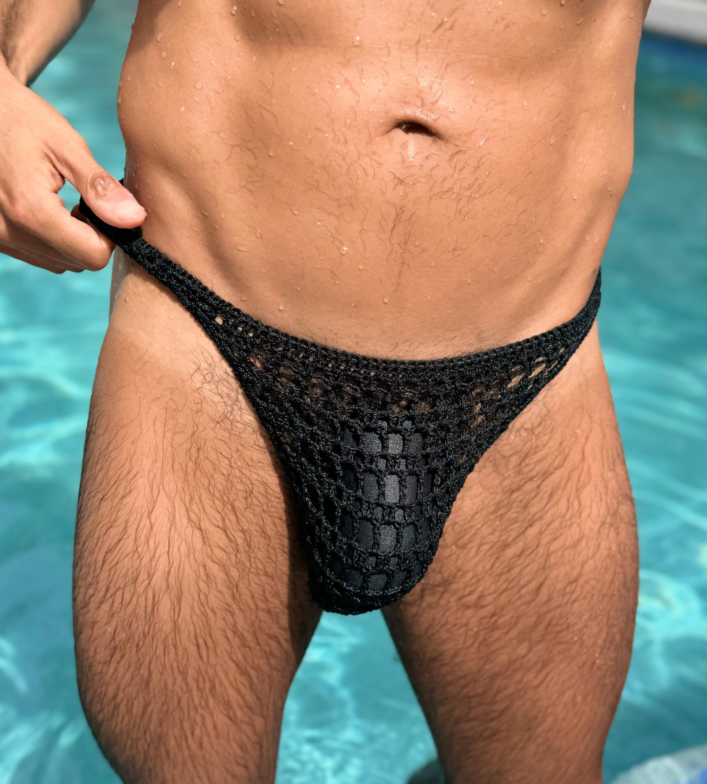 Crochet men’s erotic mesh thong on water background, minimalist beachwear aesthetic.