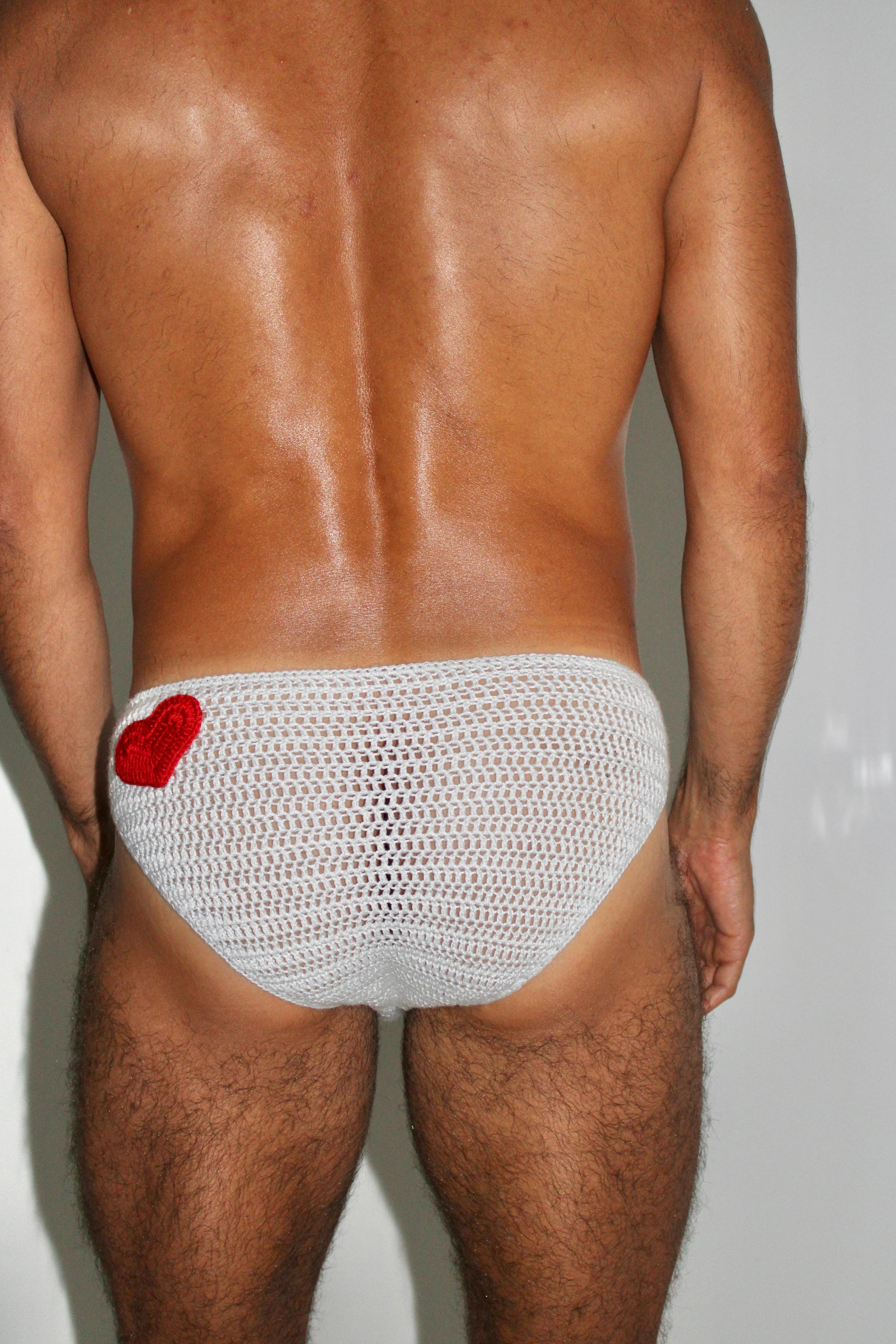 Close back side of the red heart on crochet swim briefs, highlighting adjustable handmade design.