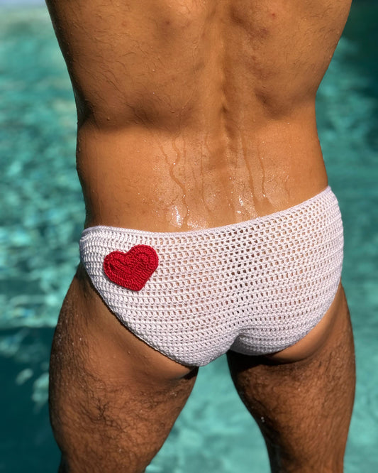 Back view of crochet men's swim briefs with red heart detail, showcasing breathable stitch pattern.
