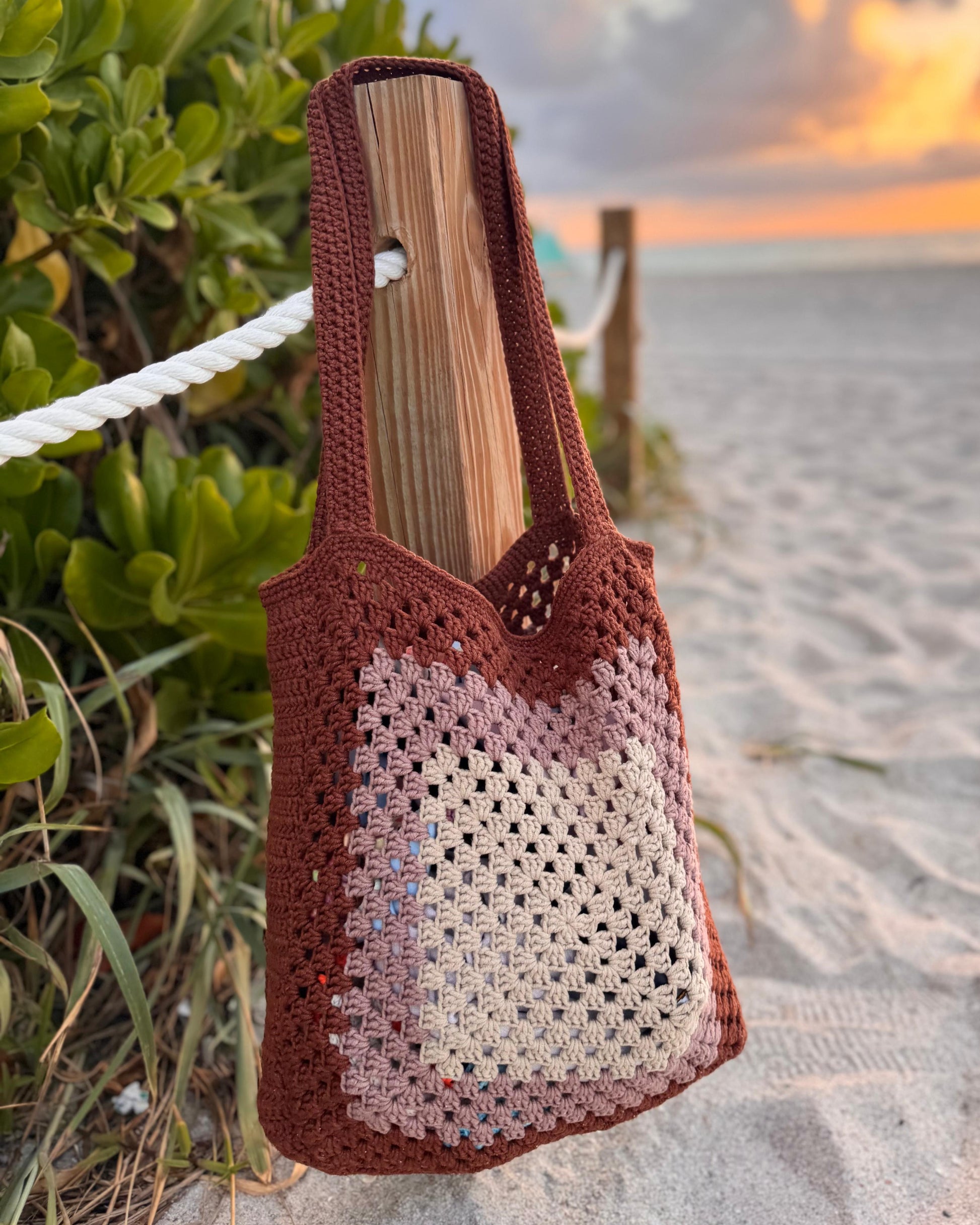 Front view of handmade crochet beach shoulder tote bag in cream color, displayed hanging on a hook.